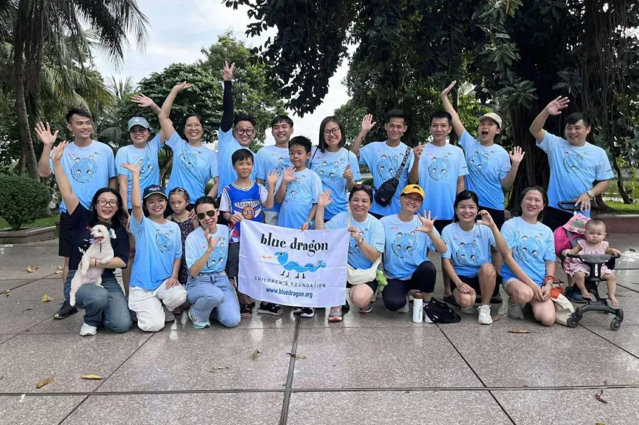 A group of Blue Dragon Walk participants holding a Blue Dragon Children's Foundation flag in 2025
